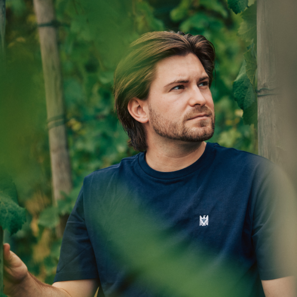 Mann mit blauem T-Shirt und weißem VDP.Adler schaut...