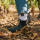 A foot is sticking out from the side of the leaves. The foot is wearing a black ankle boot, from which a white athletic sock with a black VDP eagle peeks out.